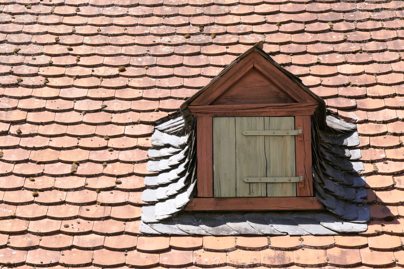 Traditionelle Holzgaube, eingefasst in ein altes Biberschwanz-Ziegeldach.