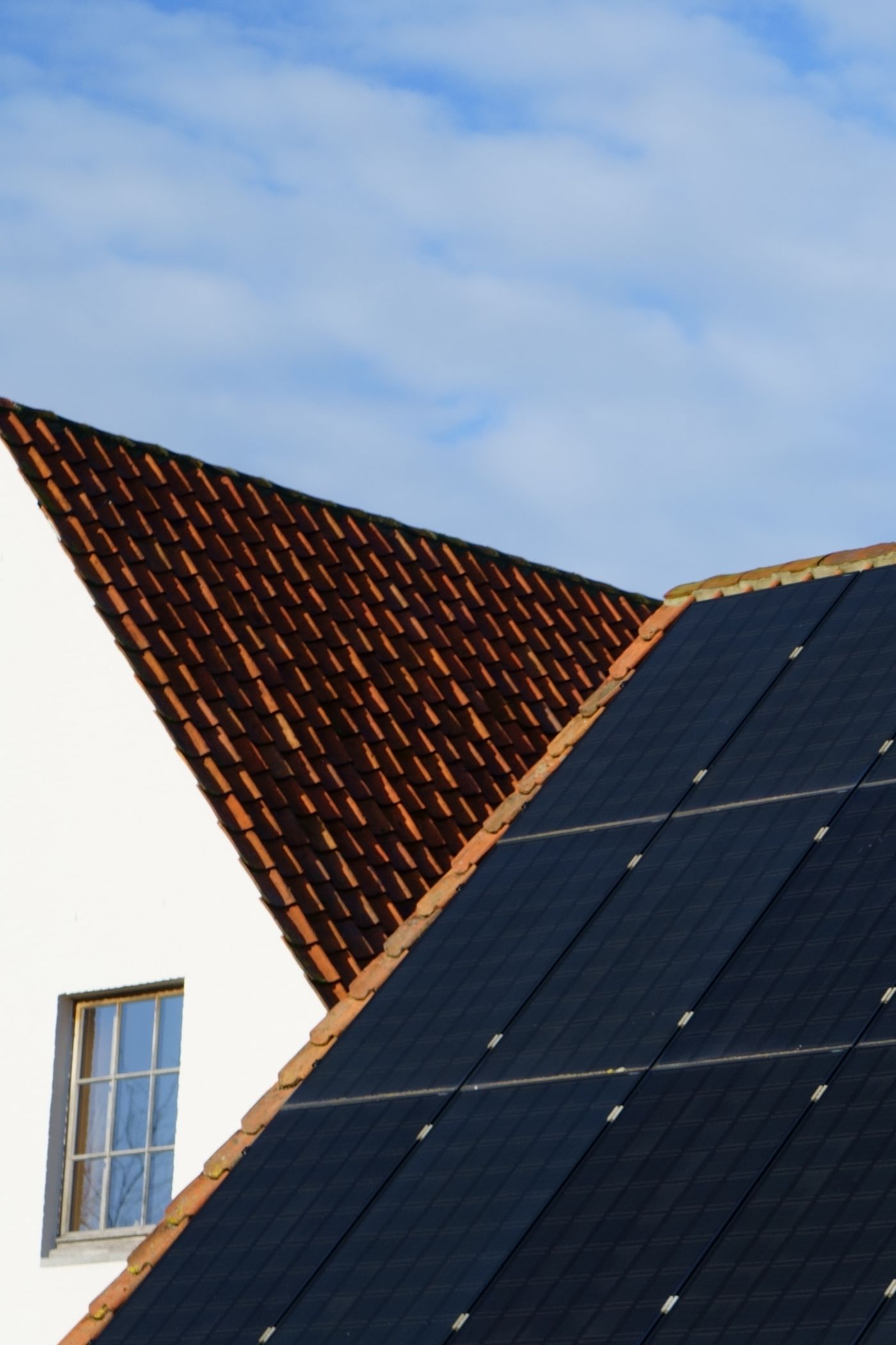 Photovoltaik-Module sauber in ein rotes Ziegeldach integriert vor blauem Himmel.